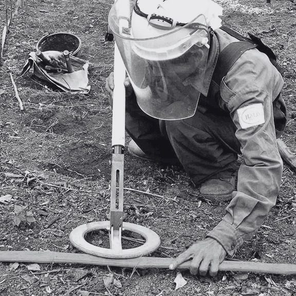 Deminer using EBEX 422 GC metal detector on a marked lane during mine clearance