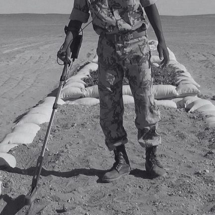 Deminer using TREX 204 M metal detector on a marked lane in desert mine clearance.