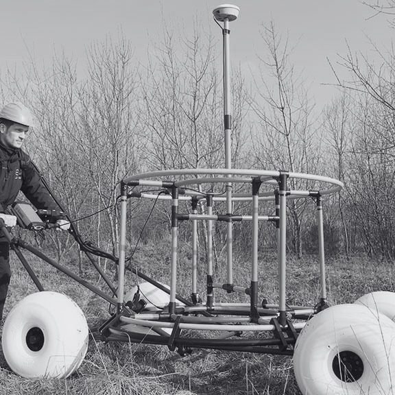 Close-up of an operator using an Ebinger detector search coil during a UXO ground survey.