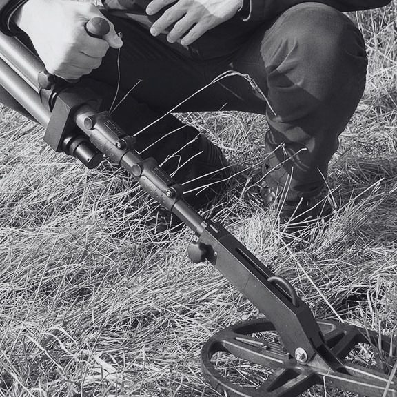 Close-up of an operator using an Ebinger detector search coil during a UXO ground survey.