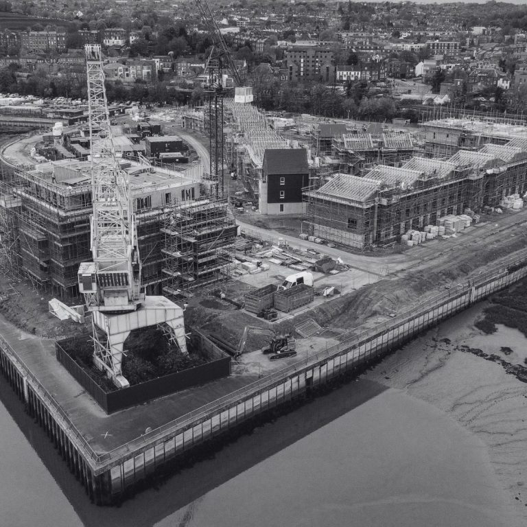 Construction site featuring industrial machinery and developing buildings beside the River Medway in Rochester, Kent, England.